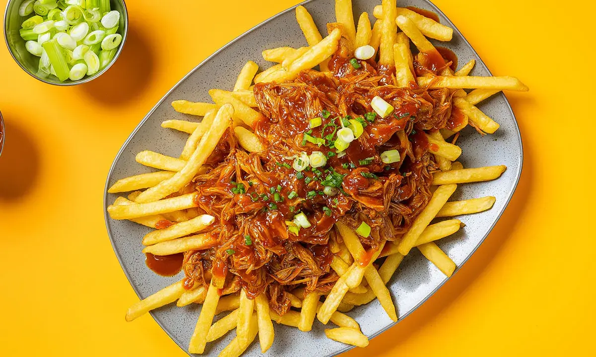 Frites croustillantes nappées d'une généreuse portion de pulled pork sauce barbecue, garnies de ciboule fraîche. Un délice !