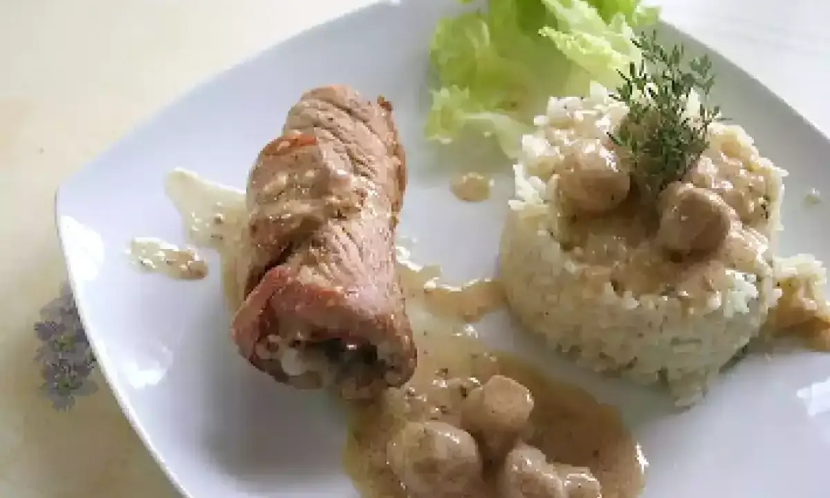 Délicieuse roulade de porc en sauce crémeuse, accompagnée d'une timbale de riz et d'une feuille de laitue.