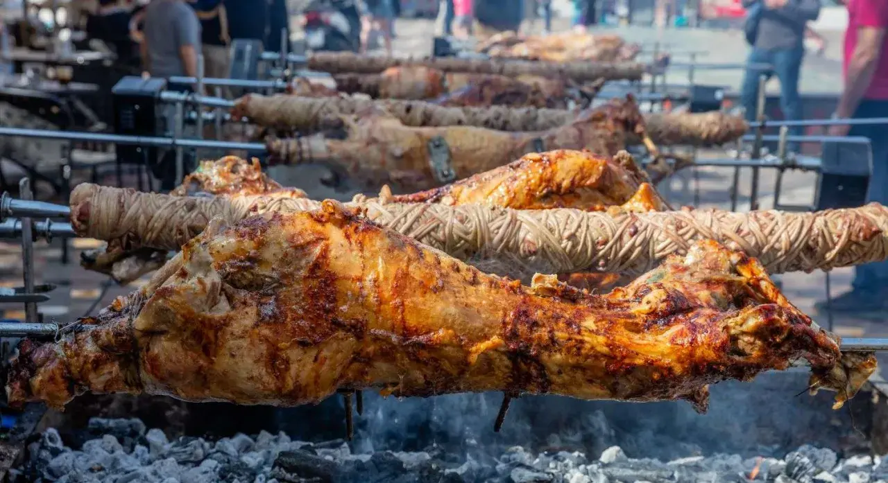 Plusieurs agneaux à la broche rôtissent lentement sur des feux de bois. La peau dorée et croustillante promet un délice savoureux.