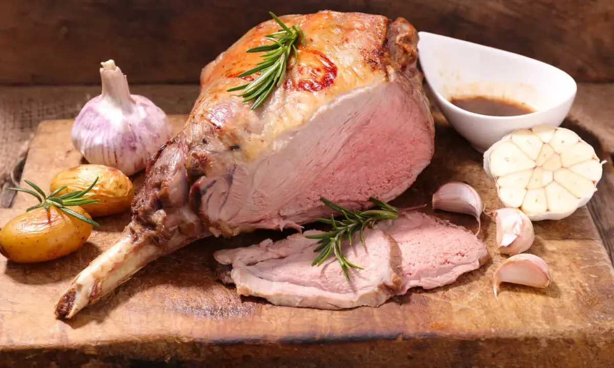 Gigot d'agneau rôti, tendre et juteux, servi avec des pommes de terre nouvelles, de l'ail et une sauce savoureuse. Un accompagnement parfait pour un repas festif.