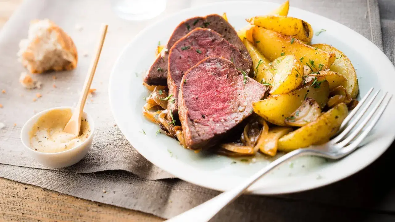 Tranches de roti de boeuf tendre, accompagnées de pommes de terre rôties et d'une sauce moutarde crémeuse.