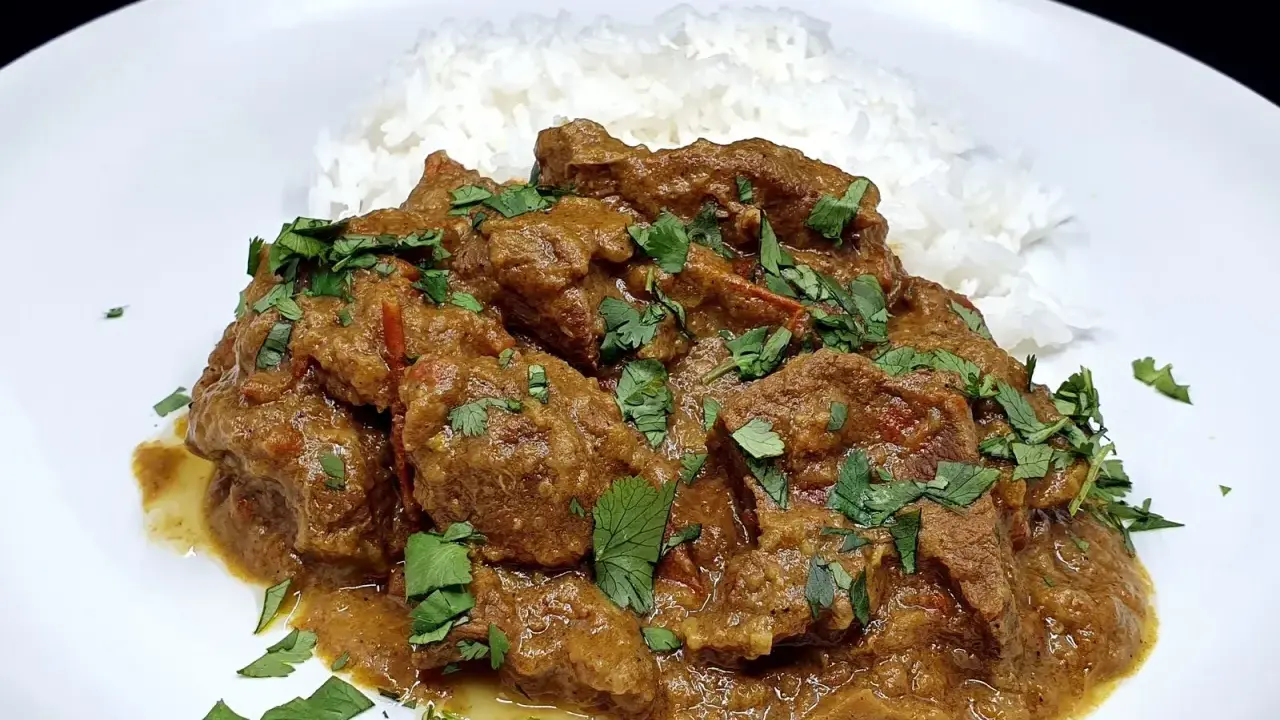 Un savoureux curry d'agneau, mijoté et garni de coriandre fraîche, servi avec du riz blanc.