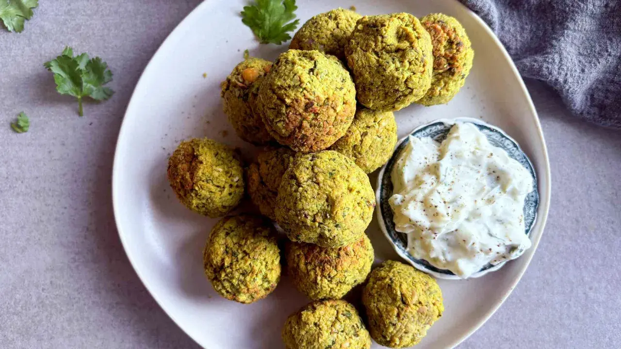 Assiette de falafels dorés, prêts à être dégustés. Une recette facile pour un plaisir garanti. Sauce blanche et coriandre pour accompagner.