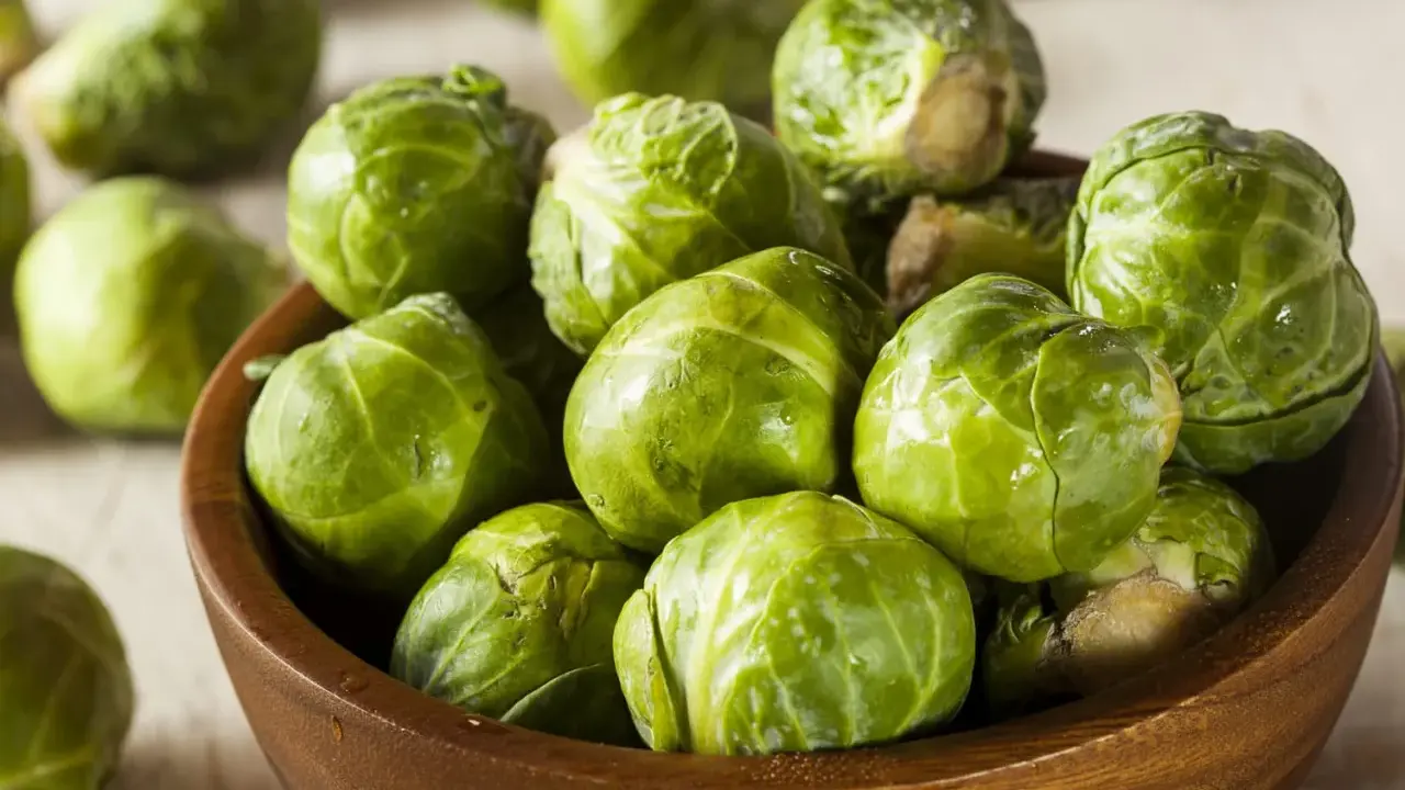 Un bol en bois rempli de choux de Bruxelles frais et verts. Ces petits légumes verts sont prêts à être cuisinés.