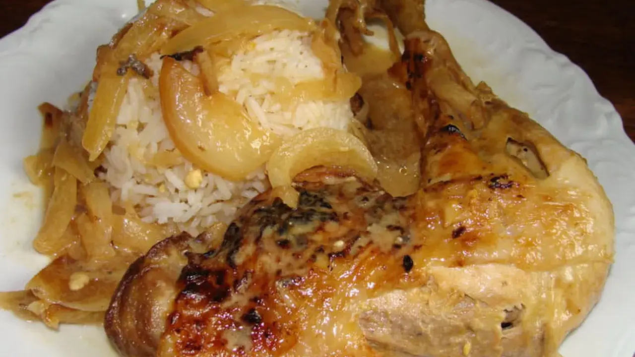 Un plat de poulet yassa savoureux avec du riz blanc et des oignons caramélisés.