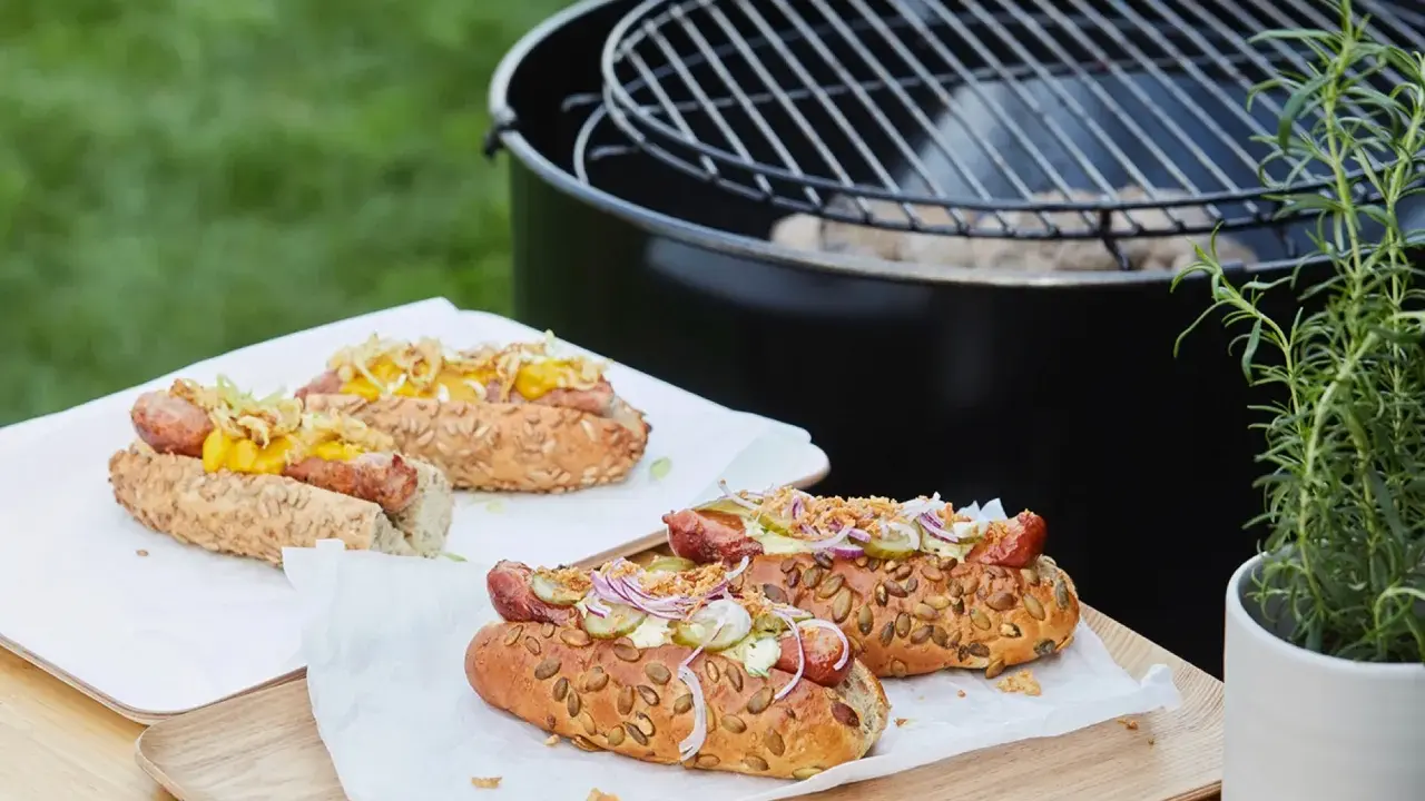 Délicieux hot dogs prêts pour un barbecue, avec des garnitures fraîches et un pain aux graines.