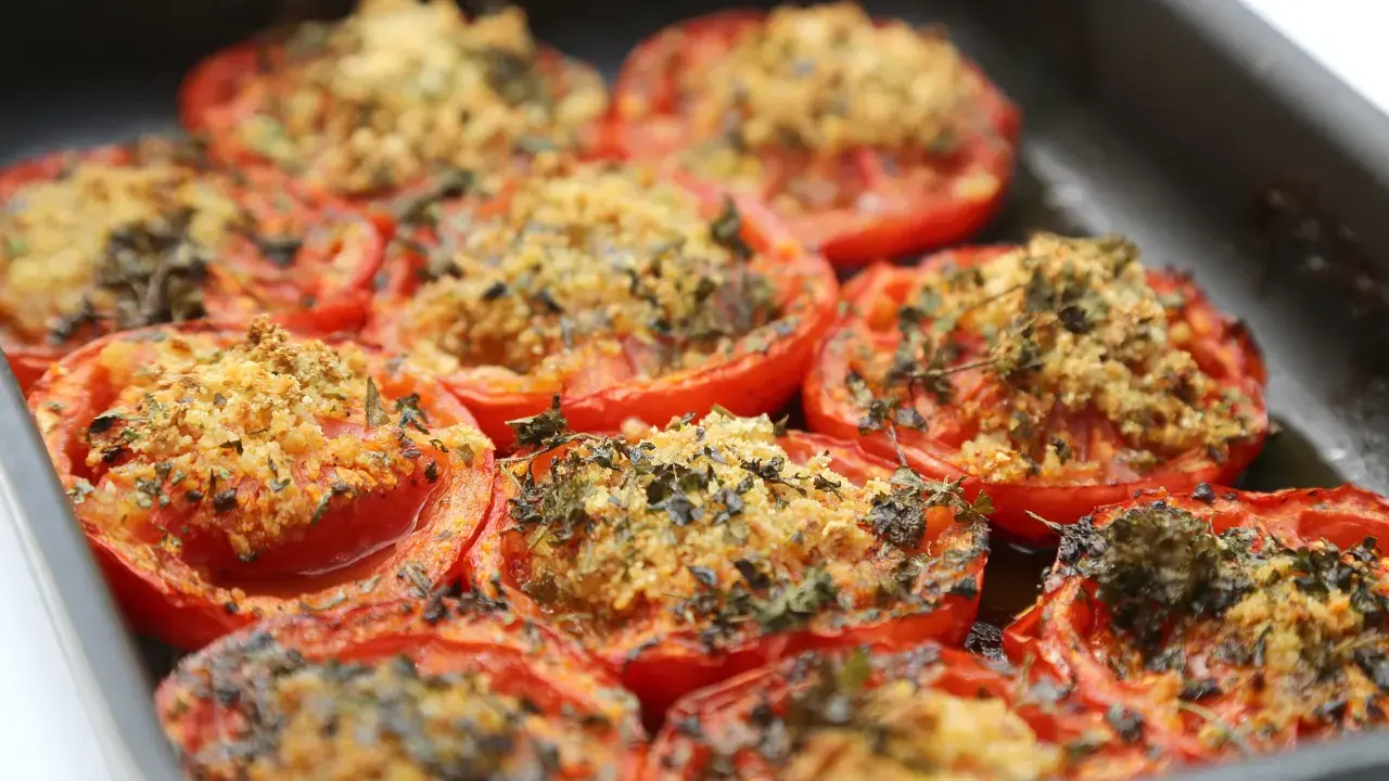 Tomates farcies au barbecue, gratinées et parsemées d'herbes fraîches, prêtes à être dégustées.
