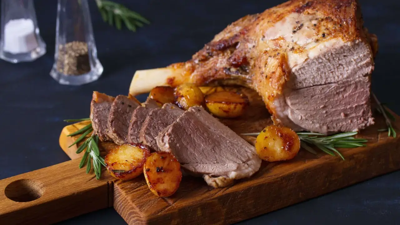Gigot d'agneau rôti, pommes de terre et romarin sur une planche en bois. Un plat parfait pour la viande pour Pâques.