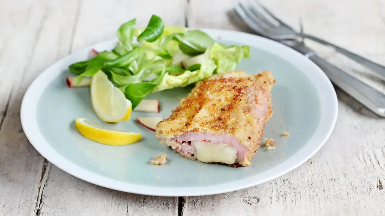 Un délicieux cordon bleu croustillant, garni de fromage fondant, servi avec une salade fraîche et des quartiers de citron.