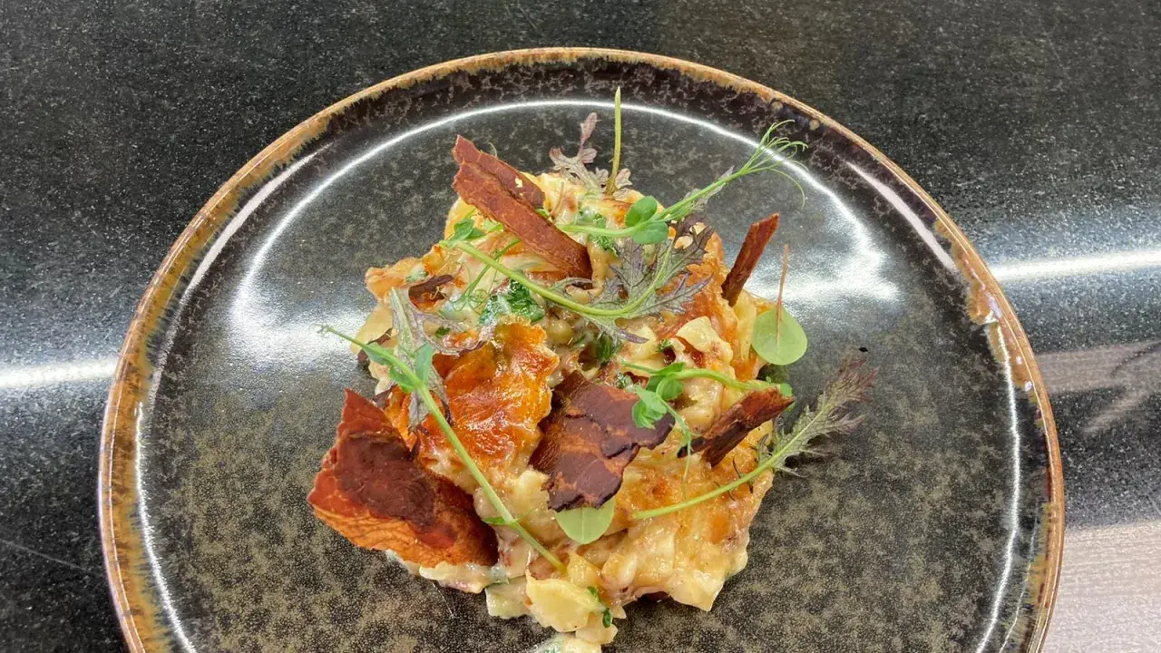 Une assiette de truffade recette, garnie de fines herbes et de lardons croustillants. Un plat réconfortant et savoureux.