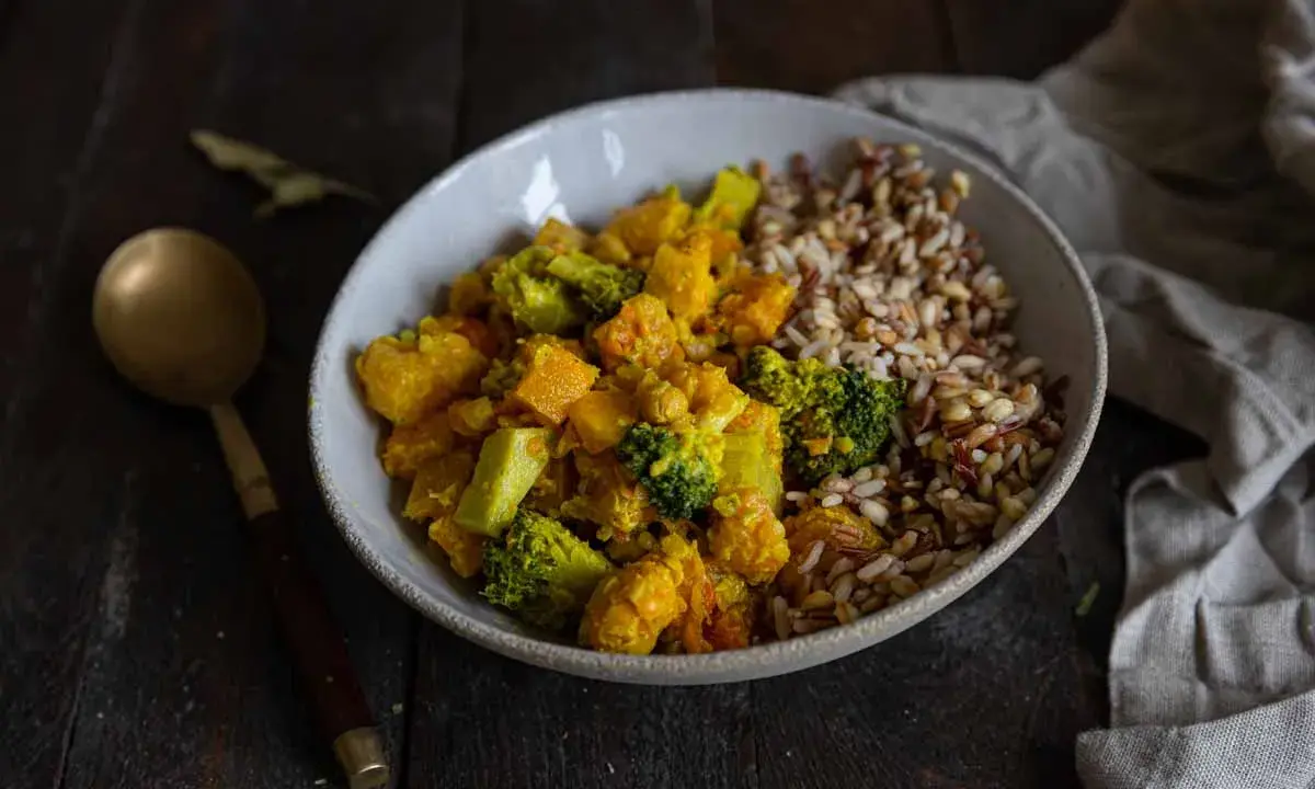 Un bol de riz et un curry de légumes coloré avec du brocoli, de la courge et des pois chiches.