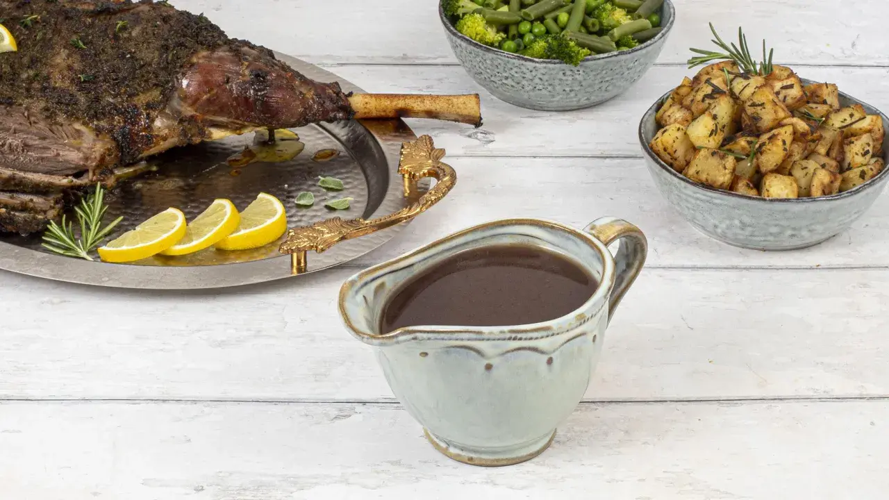 Sauce onctueuse pour accompagner une tranche de gigot d'agneau, avec des pommes de terre rôties et des légumes verts.