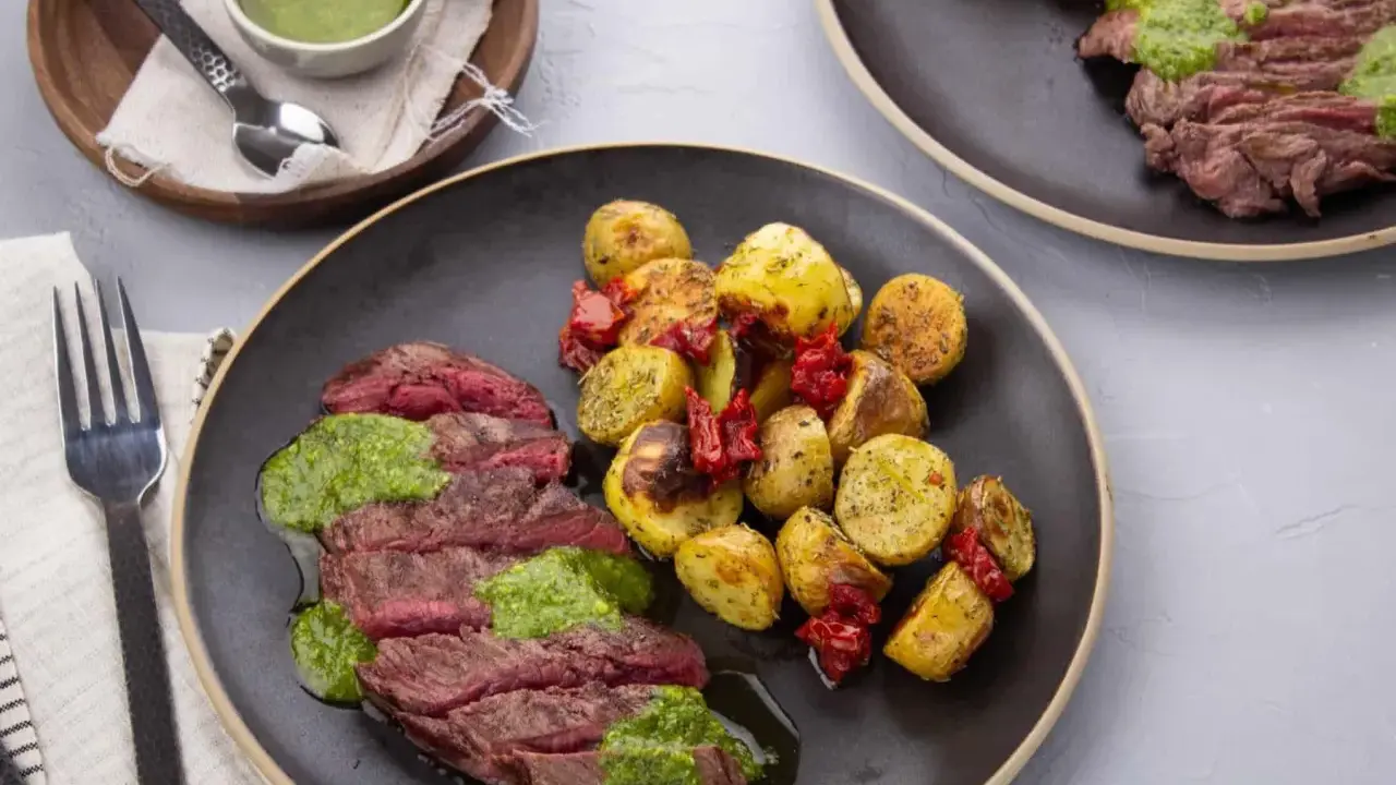 Tranches de bœuf juteux nappées de pesto, accompagnées de pommes de terre rôties et de tomates séchées. Quelle viande avec du pesto, un délice !