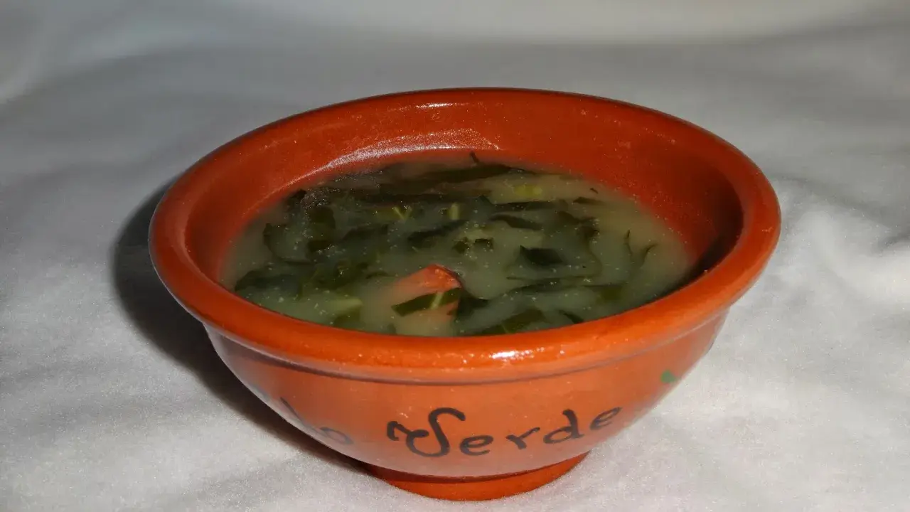Un bol en terre cuite orné du mot "Verde" contient un délicieux caldo verde, une soupe portugaise réconfortante aux légumes verts.