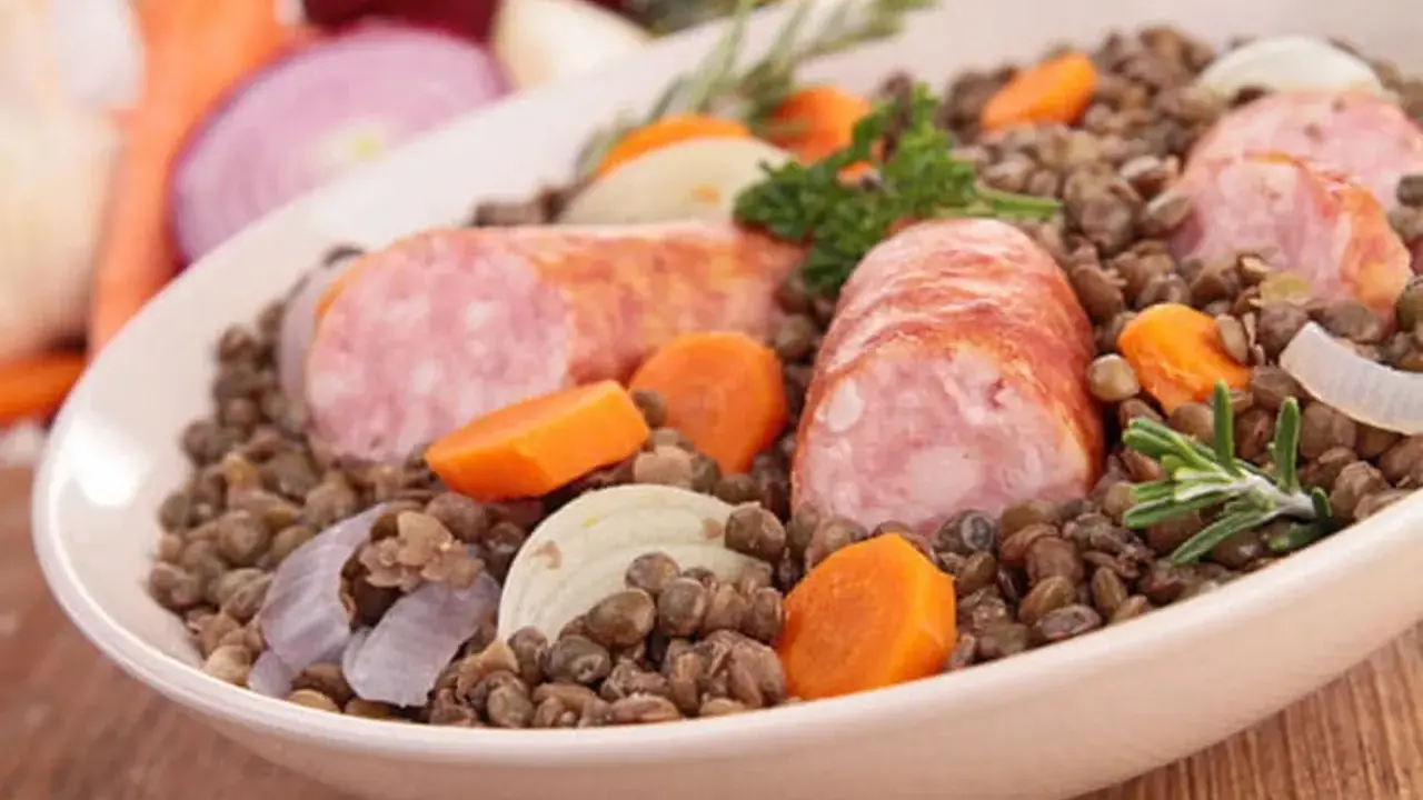 Un plat réconfortant de saucisses lentilles, garni de carottes, oignons et romarin.