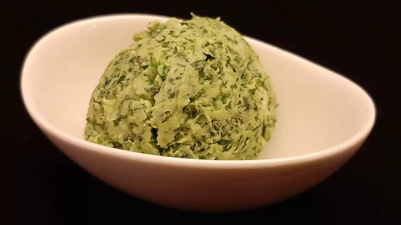 Une boule de beurre à l'ail et au persil dans un bol blanc. Parfait pour accompagner vos plats !