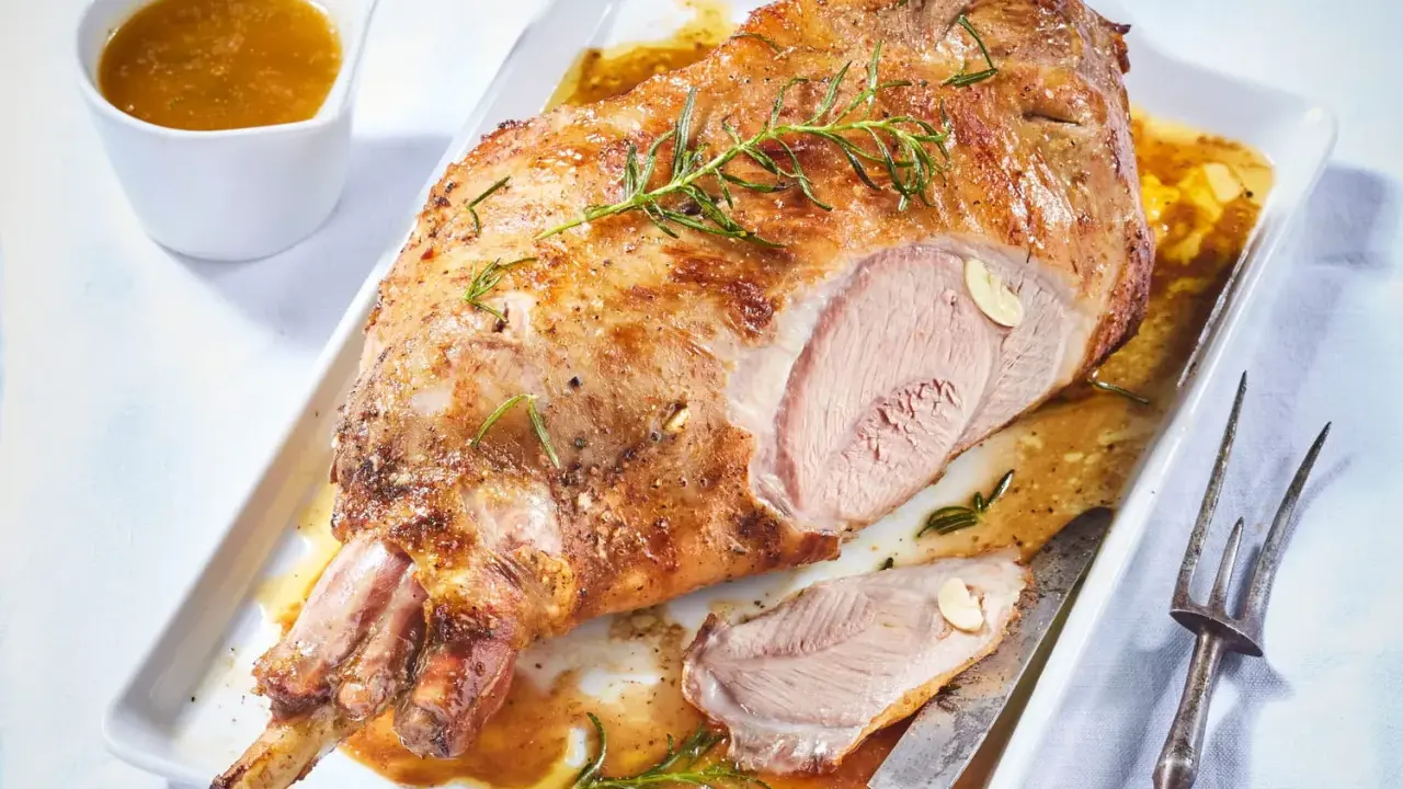 Gigot d'agneau pour 6 personnes, rôti à la perfection, servi avec sa sauce et garni de romarin.