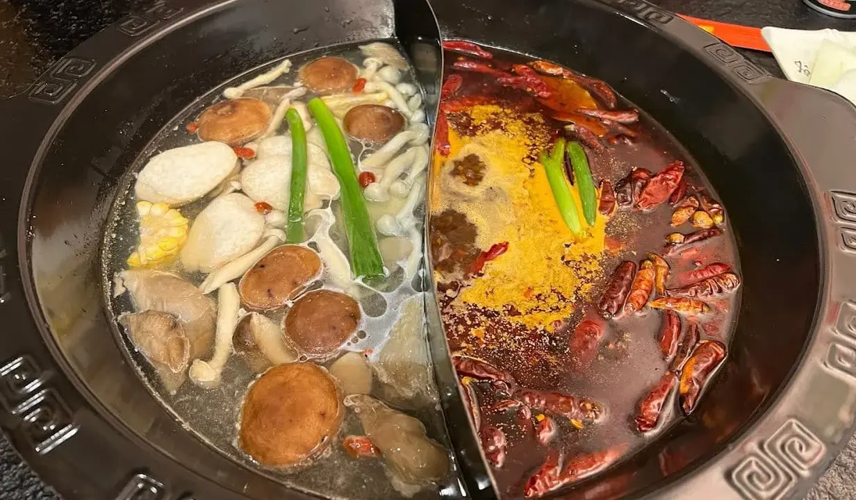 Une fondue chinoise à deux bouillons : un clair avec champignons et légumes, l'autre épicé aux piments.