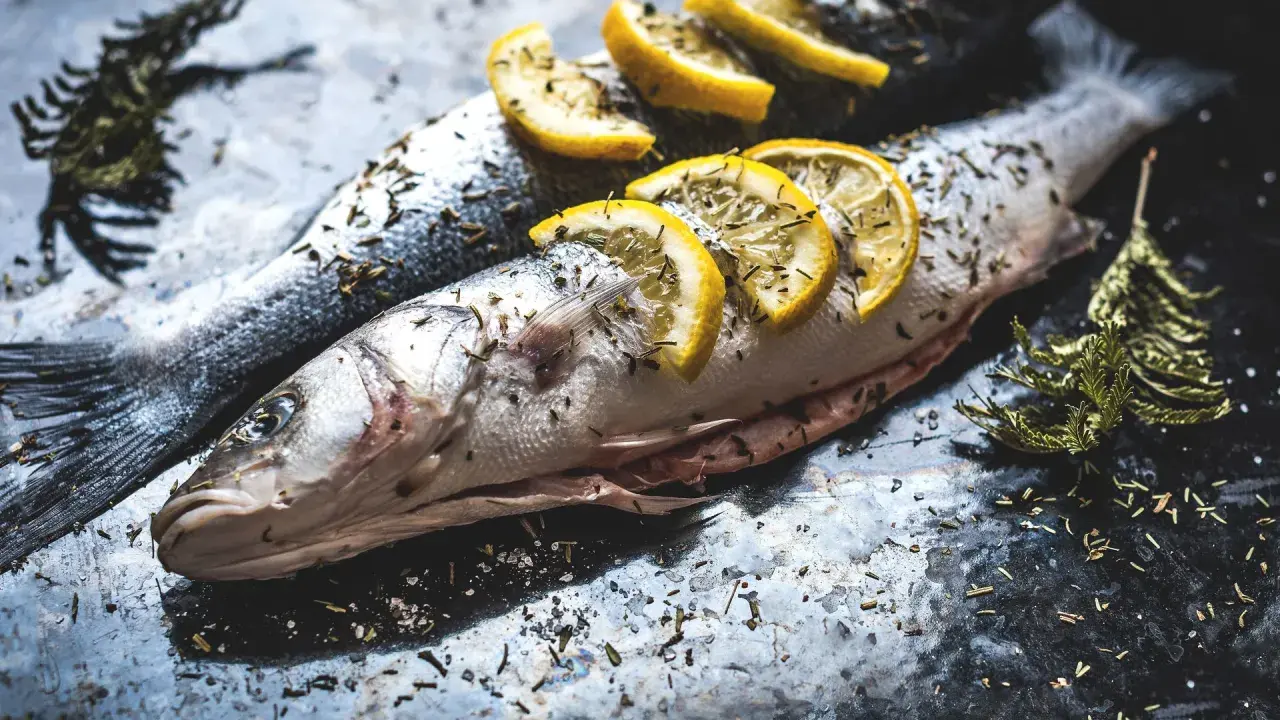 Deux poissons entiers, assaisonnés d'herbes et garnis de rondelles de citron, prêts pour un quel poisson barbecue.
