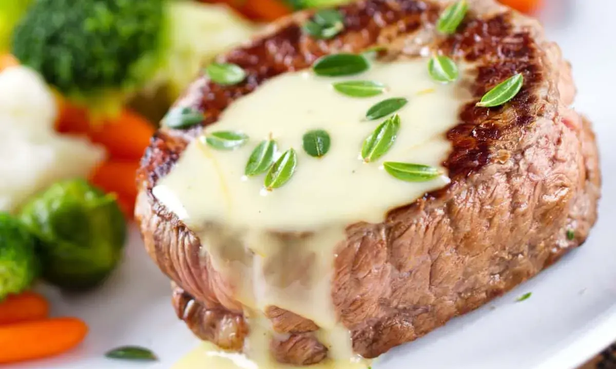 Un steak tendre nappé d'une onctueuse sauce béarnaise, accompagné de légumes verts et de carottes.