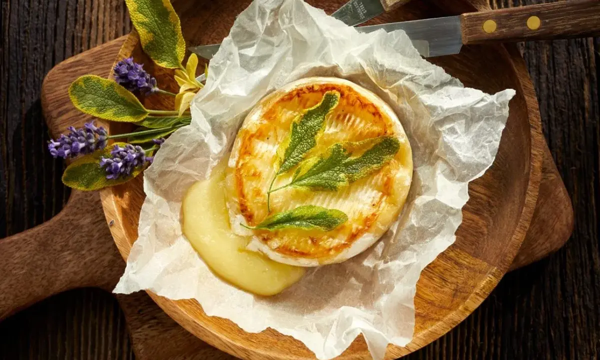 Camembert au barbecue, fondant et doré, servi sur papier sulfurisé avec des herbes aromatiques et des fleurs de lavande. Un délice à partager.