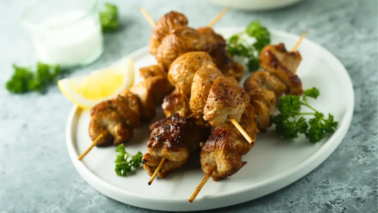 Brochettes de poulet citronnées, dorées et juteuses, garnies de persil frais et d'un quartier de citron. Un délice à savourer !