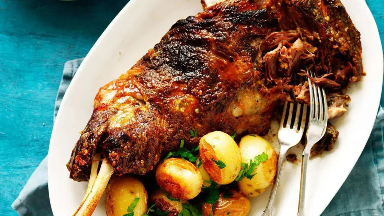 Épaule d'agneau rôtie, servie avec des pommes de terre et du persil. Le temps de cuisson de l'épaule d'agneau au barbecue Weber est parfait pour cette viande tendre.