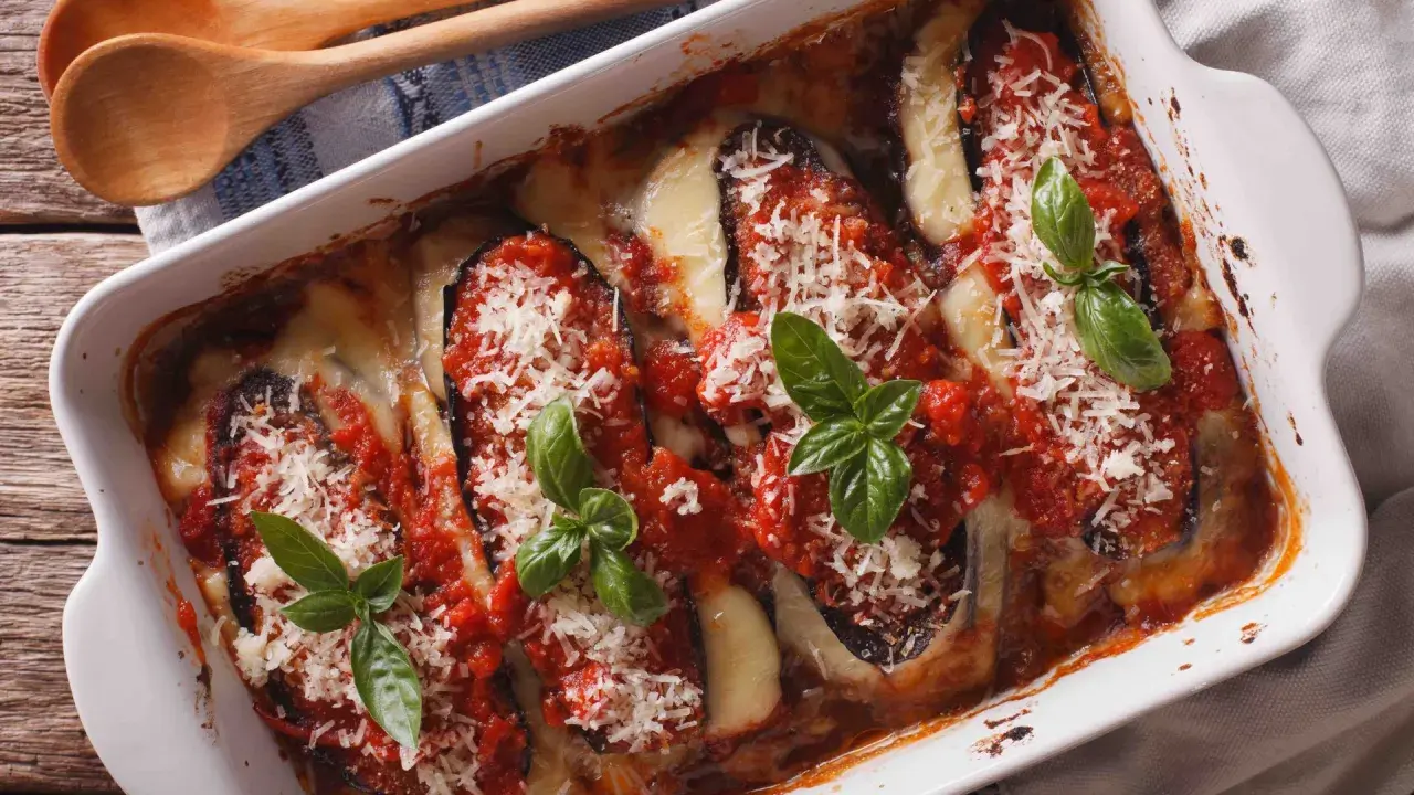 Aubergine parmigiana gratinée, garnie de sauce tomate, fromage fondant et basilic frais. Un délice italien prêt à être dégusté.