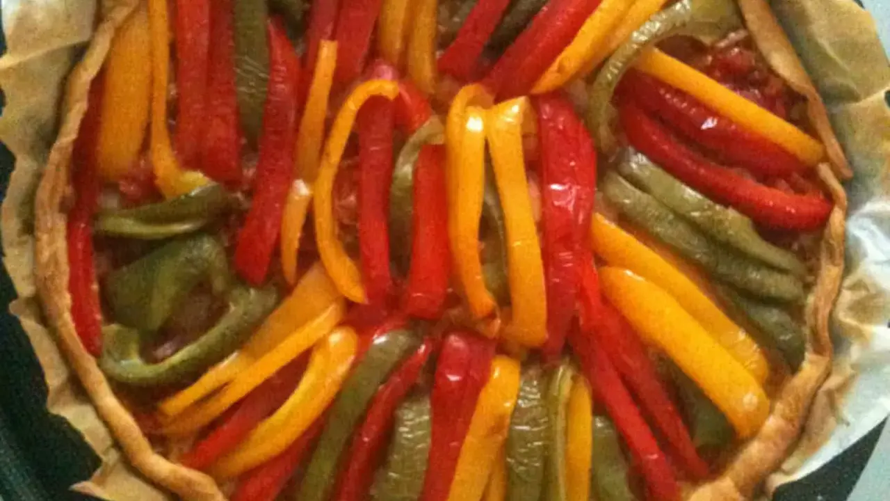 Tarte aux poivrons colorés, un délice visuel et gustatif. Les lanières de poivrons rouges, jaunes et verts forment un motif rayonnant sur la pâte dorée.