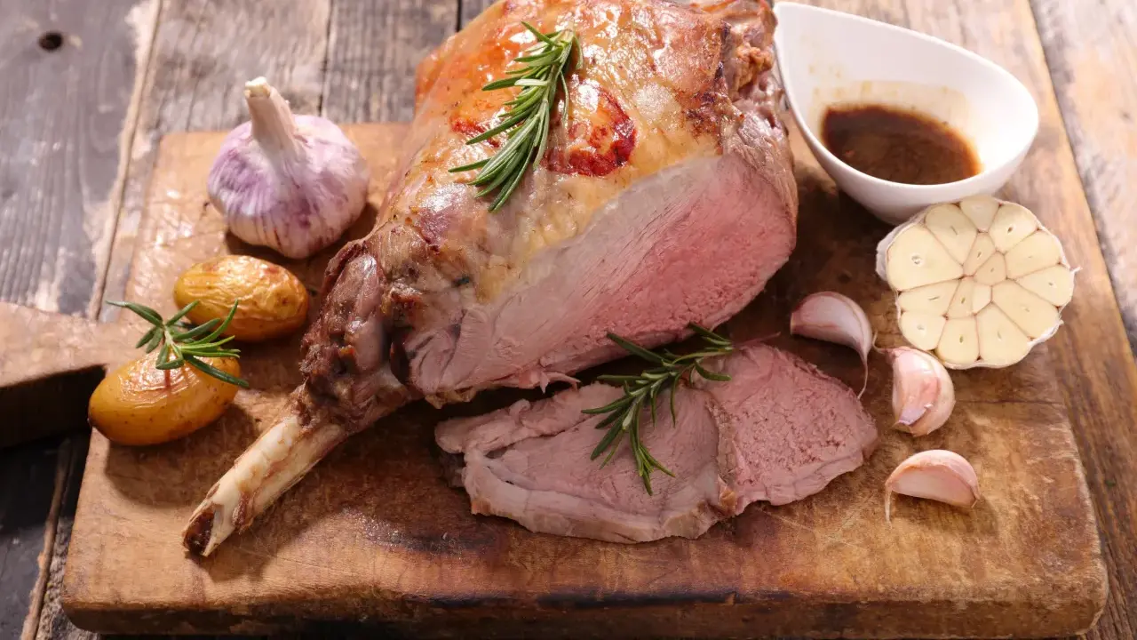Gigot d'agneau rôti, servi avec des pommes de terre, de l'ail et une sauce. Une recette gastronomique qui met l'eau à la bouche.