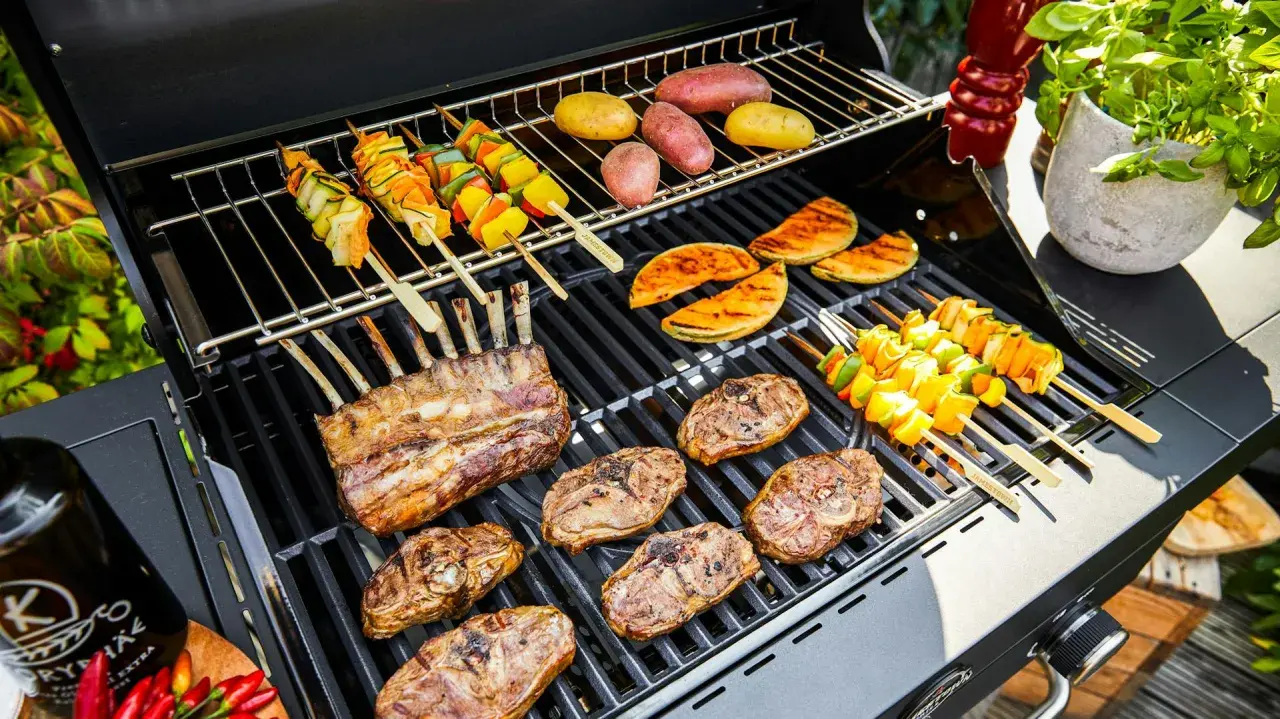 Côtelettes d'agneau, brochettes de légumes et pommes de terre sur un barbecue. La température du barbecue est parfaite pour une cuisson savoureuse.