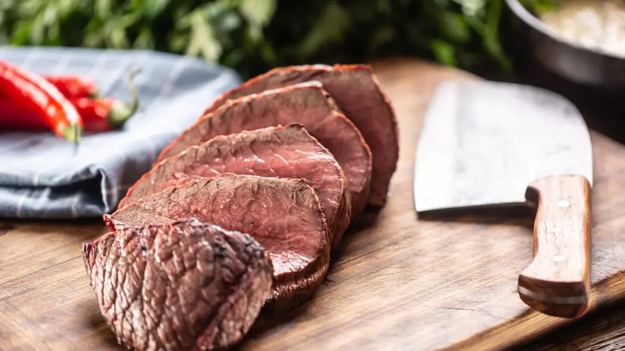 Tranches de rôti de bœuf, poivrons rouges et couteau de boucher. Que faire avec ce reste de viande cuite ?