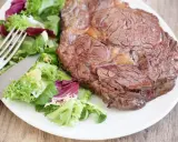 Une belle côte de bœuf juteuse, prête à être dégustée, accompagnée d'une salade fraîche. Parfait pour préparer un repas savoureux.