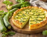 Une délicieuse tarte courgette, garnie de rondelles de courgettes fraîches et de persil, sur un fond de courgettes entières et de basilic.