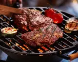 Un délicieux barbecue hivernal avec des steaks juteux, des tomates cerises et des courgettes grillées sur un feu vif.
