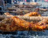 Plusieurs agneaux à la broche rôtissent lentement sur des feux de bois. La peau dorée et croustillante promet un délice savoureux.
