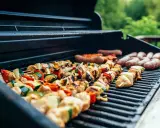 Brochettes de poulet et légumes, saucisses en cuisson barbecue gaz. L'été arrive, les grillades sont prêtes !