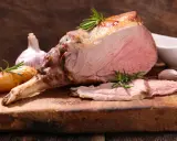 Un gigot d'agneau rôti, tendre et juteux, avec des pommes de terre et de l'ail. Ce gigot qui pleure de délice est prêt à être dégusté.