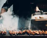 Un chef prépare un délicieux barbecue italien, des brochettes de viande fumantes sur le grill.