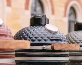 Trois barbecues kamado de couleurs différentes, prêts pour un avis. Le noir est au centre, le rouge à gauche, le gris à droite.