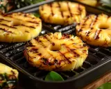 Tranches d'ananas caramélisées sur une plancha, leurs marques de grill ajoutent une touche gourmande. Un délice fruité et chaud.