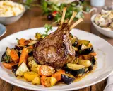 Un gigot d'agneau rôti, prêt pour un accompagnement gigot d'agneau pour Noël, servi avec des légumes de saison grillés.