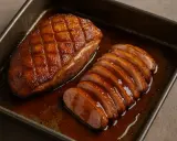 Un magret de canard au four, entier et tranché, baignant dans sa sauce caramélisée. Un délice croustillant et fondant.