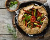 Tarte aux légumes colorée, garnie de tomates, courgettes et aubergines, prête à être dégustée.