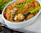 Un délicieux crumble salé aux légumes et riz, servi dans un plat blanc, avec une fourchette verte prête à déguster.