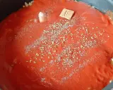 Sauce tomate maison mijote dans une poêle, agrémentée d'herbes et d'un cube de bouillon.