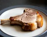 Une côte de porc dorée et juteuse, prête à être dégustée, repose sur une assiette.