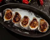 Cinq huîtres au barbecue, grillées et savoureuses, servies sur un lit de gros sel.