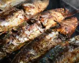 Plusieurs poissons entiers, dorés et appétissants, cuisent sur un barbecue au charbon. Quel poisson au barbecue charbon, une merveille !