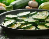 Tranches de courgettes assaisonnées cuisant dans une poêle, prêtes pour une délicieuse recette de courgette à la poêle.